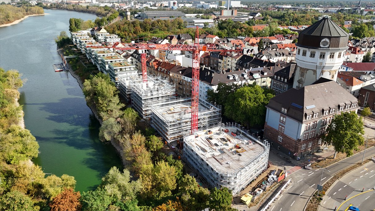 Die eingerüsteten Neubauten am Neckarufer, rechts ein historisches Turmgebäude