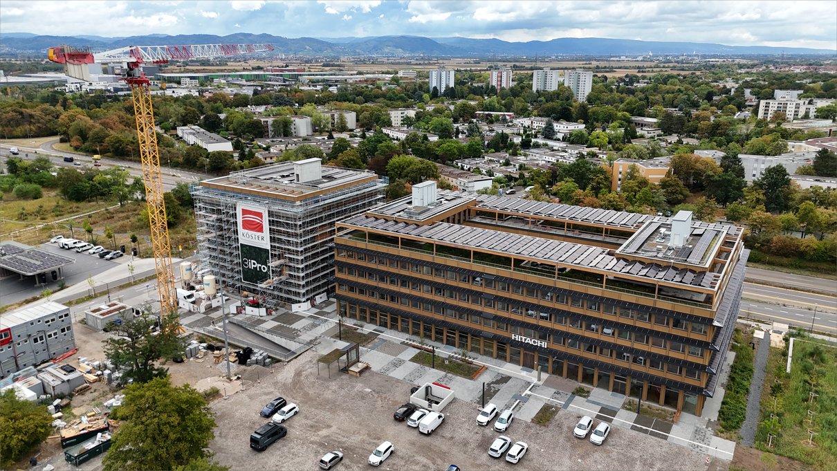 Fassadengerüst an Haus B, rechts das bezogene Hitachi-Gebäude in Holzhybridbauweise
