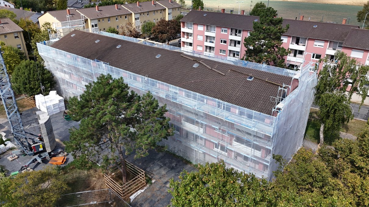 Fassadengerüst mit Netzverkleidung über alle Geschosse, links Materiallager und Kran